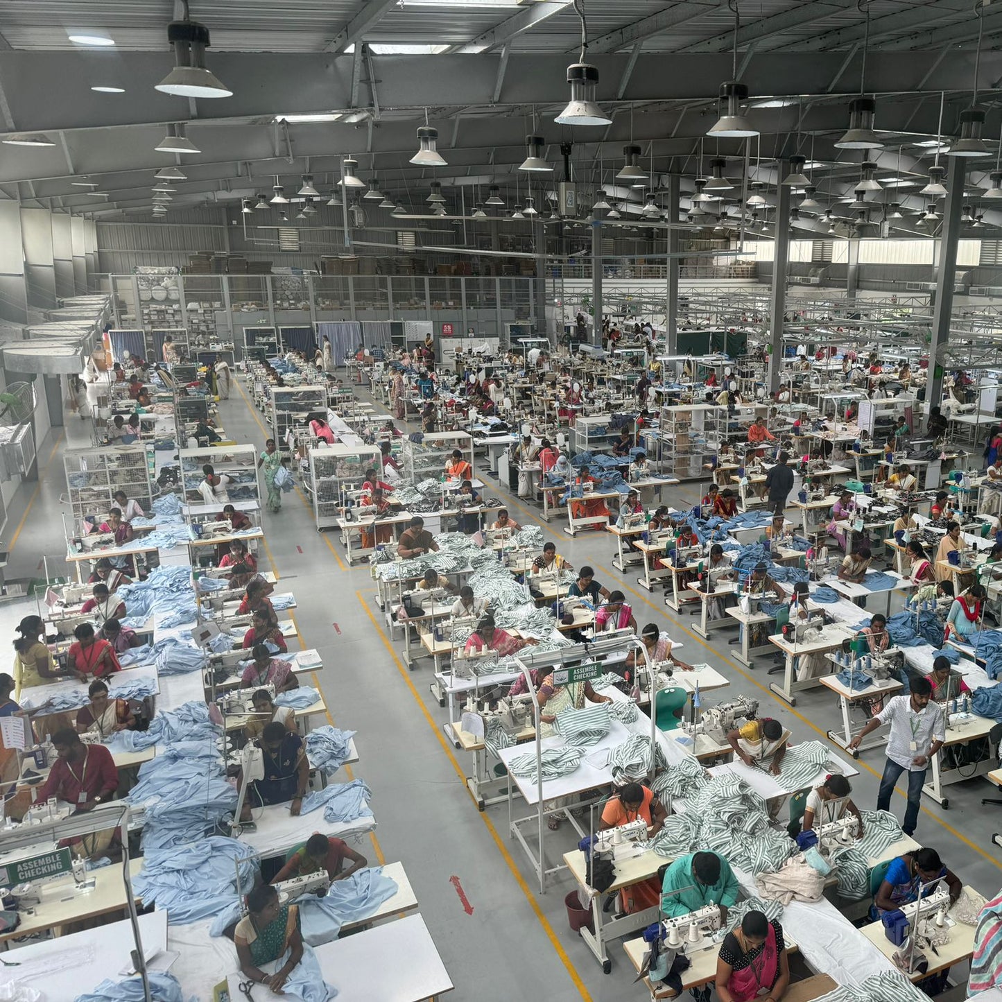 Blick in die ebeneerdige Produktionshalle in Indien auf ca. 500 Arbeitsplätze. Tageslicht ergänzt das Kunstlicht. Große Ventilatoren sorgen für ein gutes Raumklima. PV-anlagen auf dem Dach liefern Energie für Maschinen und Licht. Mittags erklingt ein Gong und alle machen eine gemeinsame Teepause, die sie im betriebseigenem Garten verbringen. Die Produktion wurde in einer Region errichtet, in der die Arbeitskräfte leben Die Frauen werden samt Kinder von Bussen hin/her gebracht.
Betriebs-KITA und Schule!