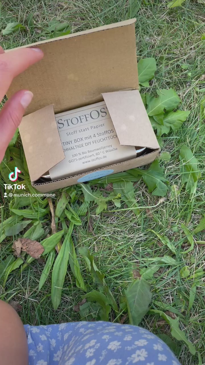 In diesem Film erklärt Sophie im sonnigen Garten auf einer Wiese sitzend, wie man sich aus den vier Stofftaschentuchröllchen, wir nennen sie StoffOS, auch aus den bedruckten StoffOS, in der gut schließenden Tiny Box aus Edelstahl DIY, also Do IT Yourself Feuchttücher herstellt. Dazu beträufelt sie jeweils eines der Röllchen mit einem Esslöffel Wasser. Später gibt sie ein Duftöl ihrer Wahl dazu und hat dadurch aus einfachen Feuchttüchern Erfrischungstücher gewonnen.
