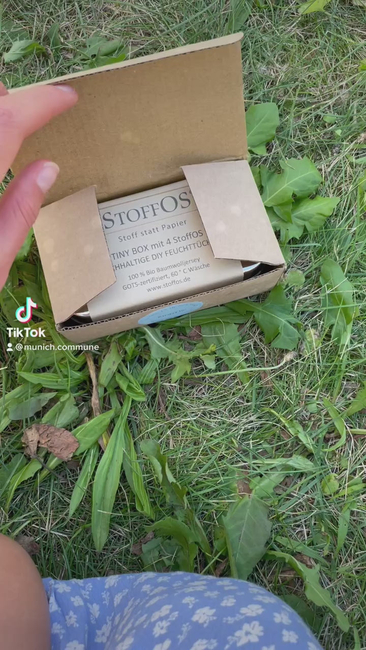 In diesem Film erklärt Sophie im sonnigen Garten auf einer Wiese sitzend, wie man sich aus den vier Stofftaschentuchröllchen, wir nennen sie StoffOS, auch aus den bedruckten StoffOS, in der gut schließenden Tiny Box aus Edelstahl DIY, also Do IT Yourself Feuchttücher herstellt. Dazu beträufelt sie jeweils eines der Röllchen mit einem Esslöffel Wasser. Später gibt sie ein Duftöl ihrer Wahl dazu und hat dadurch aus einfachen Feuchttüchern Erfrischungstücher gewonnen. 