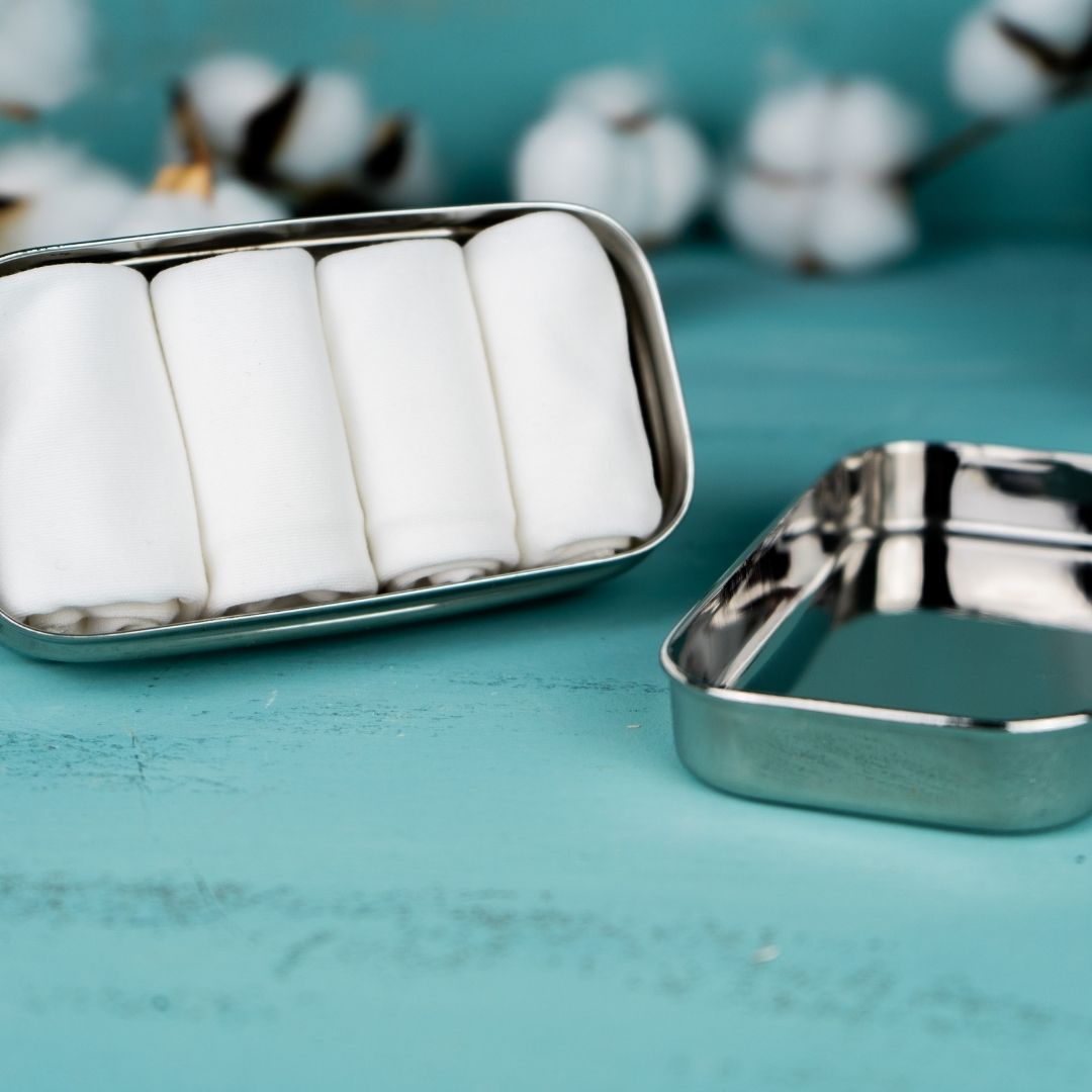 Stofftaschentücher, weiß, 4er Set in Tiny Box für DIY Feuchttücher. Die 6,5 cm breite, 12 cm lange und im geschlossenem Zustand 4 cm hohe Edelstahlbox ist Hochglanz poliert. Man kann sich darin spiegeln. Darin liegen vier naturweiße Stofftaschentücher aufgerollt nebeneinander.