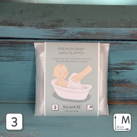 Packung mit drei Babypflegetüchern in Premium Qualität. Größe M, 35 x 35 cm. Die Zeichnung zeigt ein Baby in einer Badewanne sitzend, das von einer Hand mit einem weißen Waschlappen gewaschen wird.