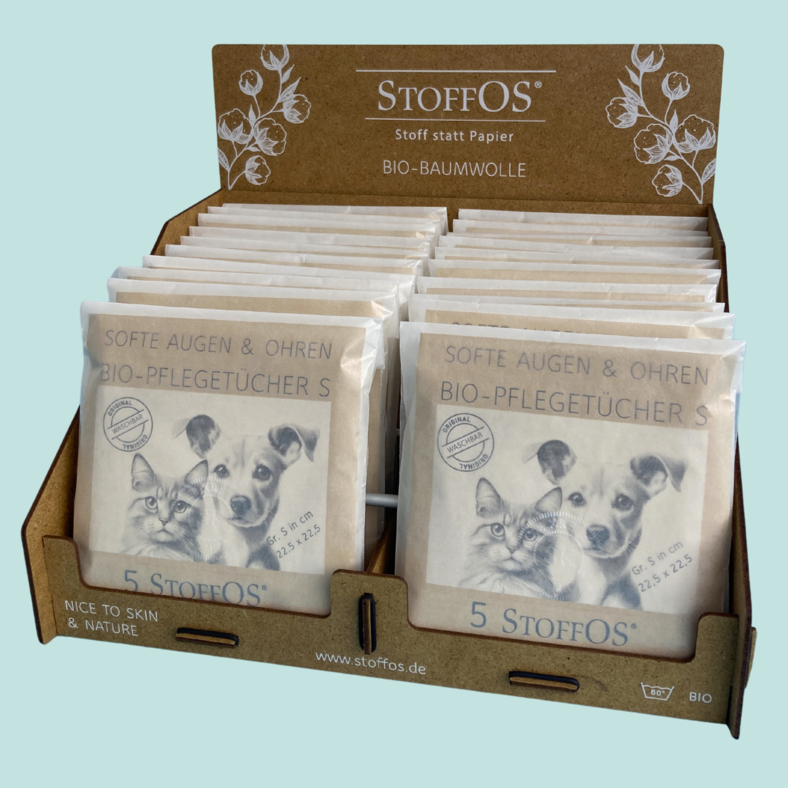 Das Display aus braunem Pressholz ist mit dem StoffOD Logo und Claim: Stoff statt Papier in weiß verziert. Daneben sind Baumwollzweige mit reifen BAumkapseln abgebildet. Zeichnungen von Hund und Katzenkopf auf der Verpackung der Tüten.